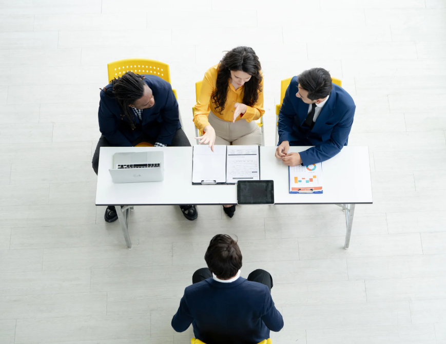 Job candidate sitting across from two interviewers at a table during a professional interview.